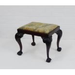 A 19th century mahogany stool. the floral upholstered top on carved leaf supports with claw and ball