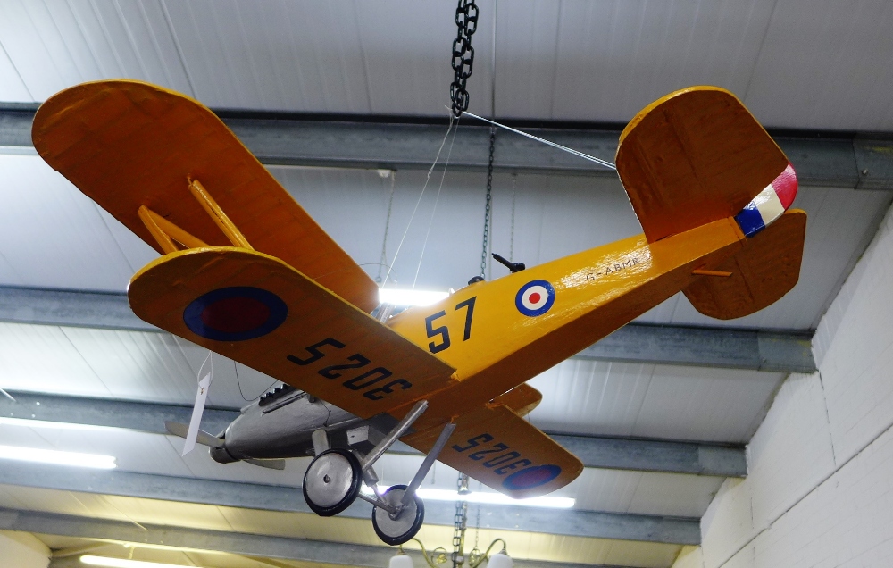 A model bi-plane painted in yellow and silver with wooden body and painted paper wings, 95 x 95cm