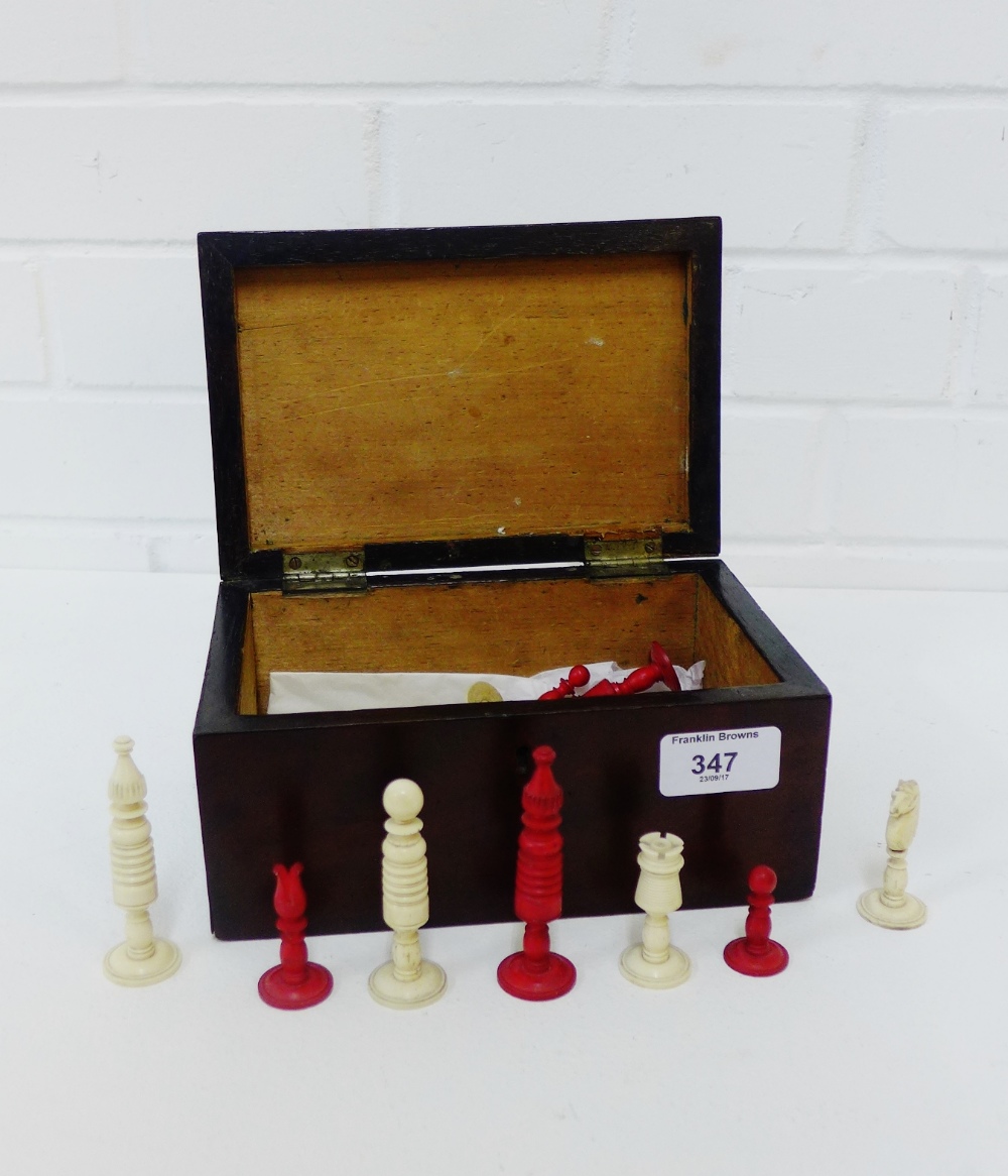 A mahogany box containing a set of bone and stained red chess pieces