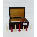 A mahogany box containing a set of bone and stained red chess pieces