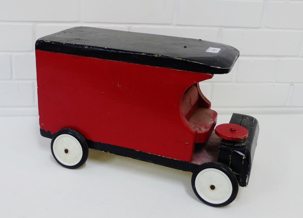 A vintage red and black painted wooden bus with plastic wheels, 43cm long