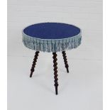 A Gypsy table, the circular top with pale blue upholstery, raised on barley twist supports, 63 x