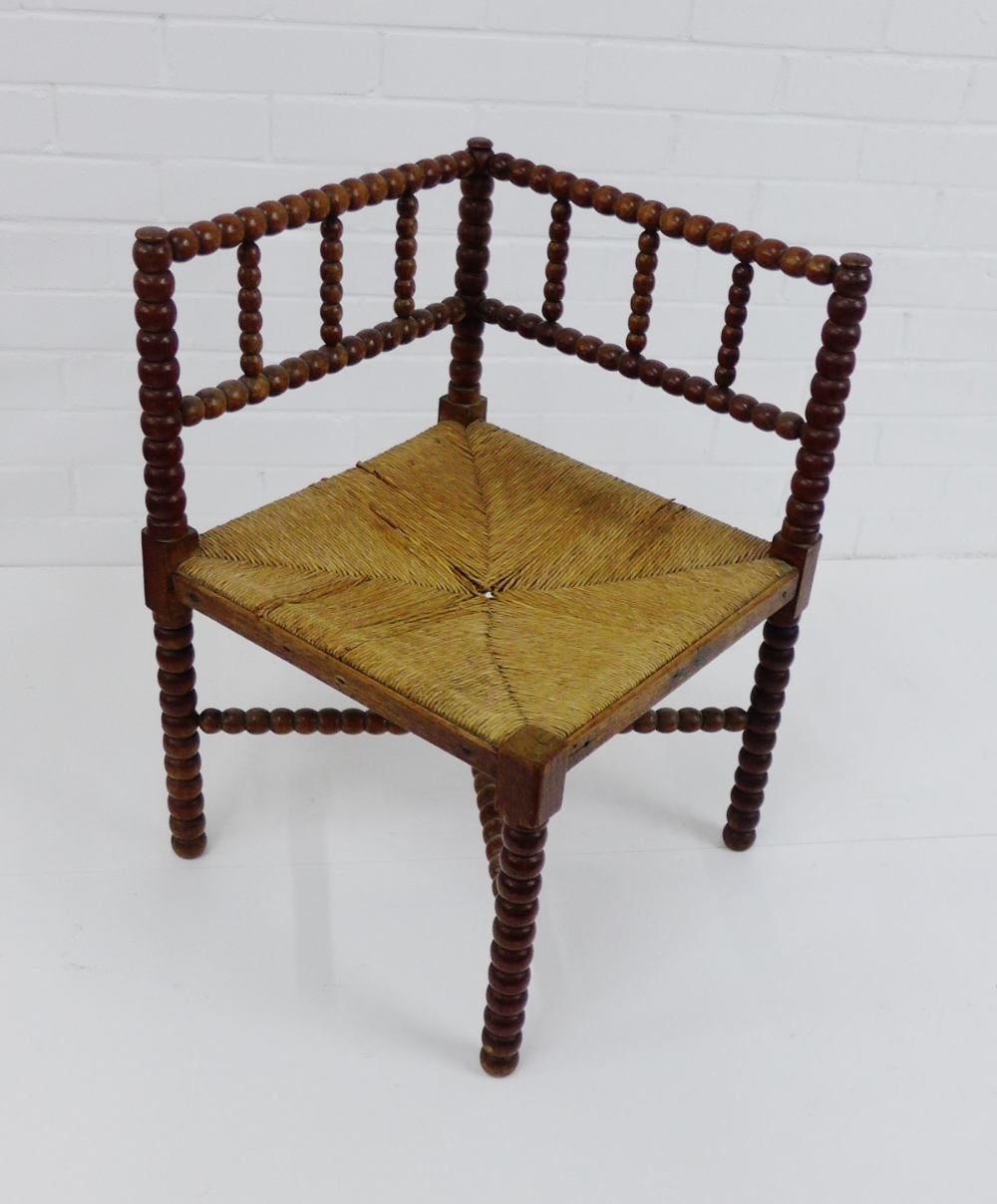 An Arts & Crafts bobbin turned corner chair with rush seat 65 x 62cm