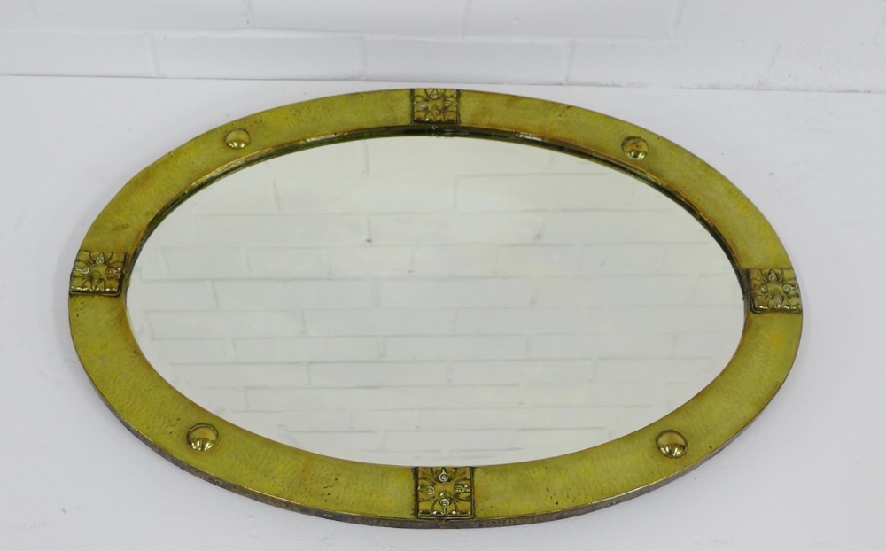 An Arts & Crafts brass framed oval mirror, 70 x 50cm