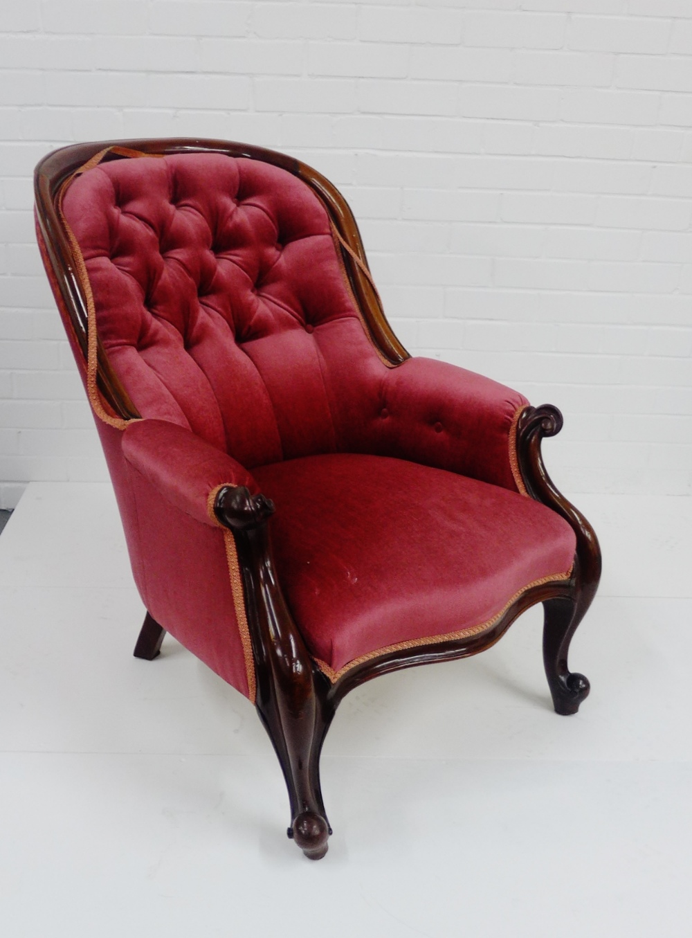 A mahogany show frame button back armchair, upholstered in red velvet fabric, 88 x 64cm