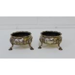 A pair of George III silver salts, each with floral embossed pattern to the body and raised on