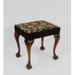 A mahogany framed footstool with upholstered top and cabriole supports with claw and ball feet, 50 x