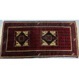 An Eastern rug, the red field with two diamond lozenge motifs within multiple geometric borders,