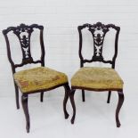 A pair of mahogany framed side chairs, with carved top rails over foliate pierced backs and