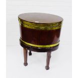 An early 19th century mahogany and brass bound cellarette of oval form, the stand with tapering