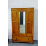 An oak wardrobe, the pediment top over a central mirrored door and pair of panelled doors, with a