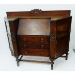 An Art Deco oak ledgeback bureau, the fall front flanked by glazed and panelled cupboard doors, with