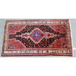 An eastern rug with red foliate field and central medallion, 176 x 94cm