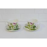 Two Roy Kirkham 'Redoute Roses' cup and saucers, (2)