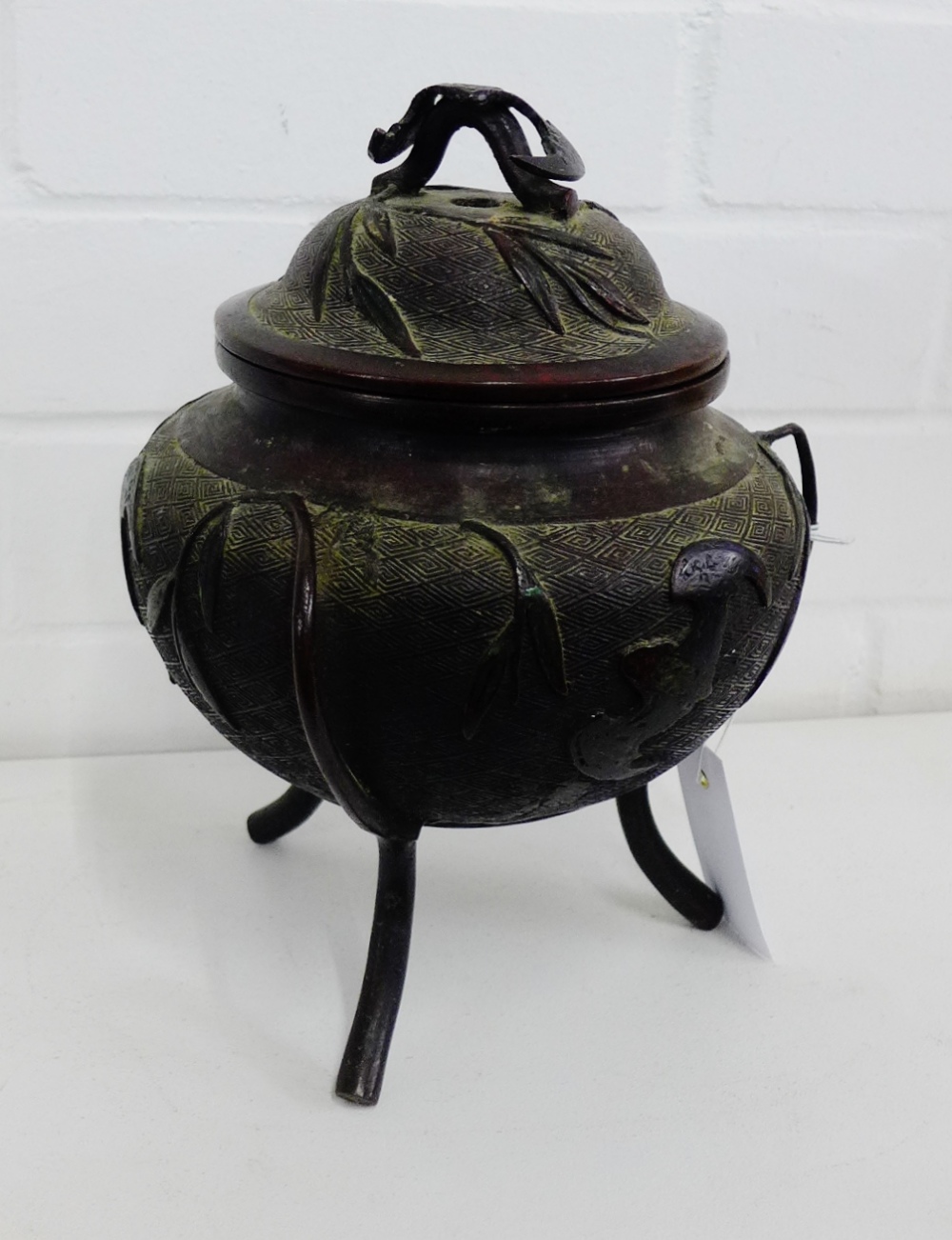 A Chinese bronzed tripod censor and cover, the lid with the handle in the form of a bat, it has a