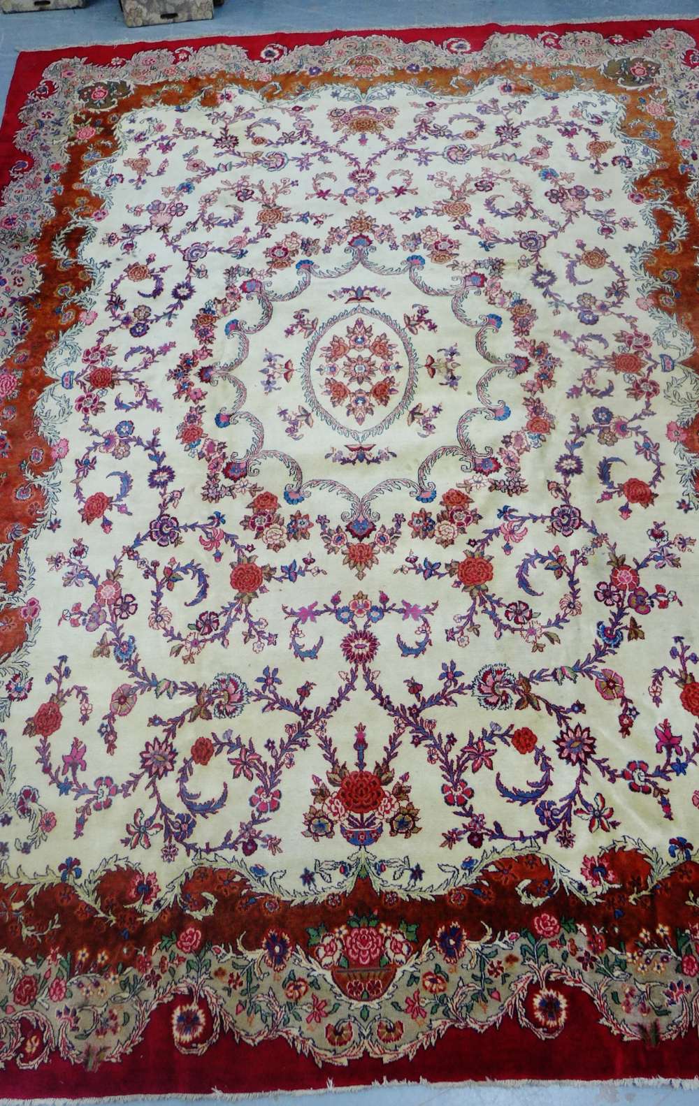 A large rug, the cream field with allover floral pattern within crimson borders, 420 x 312cm