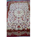 A large rug, the cream field with allover floral pattern within crimson borders, 420 x 312cm