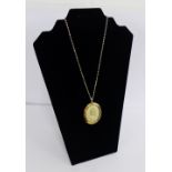 A 9 carat gold locket of oval form with suspension loop and glazed front, on a 9 carat chain, locket