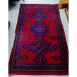 A Turkish red rug, the red field with triple medallions and multiple borders, 226 x 138cm