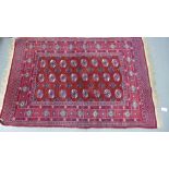 A Bokhara rug, the red field with three rows of eight medallions within multiple flowerhead borders,