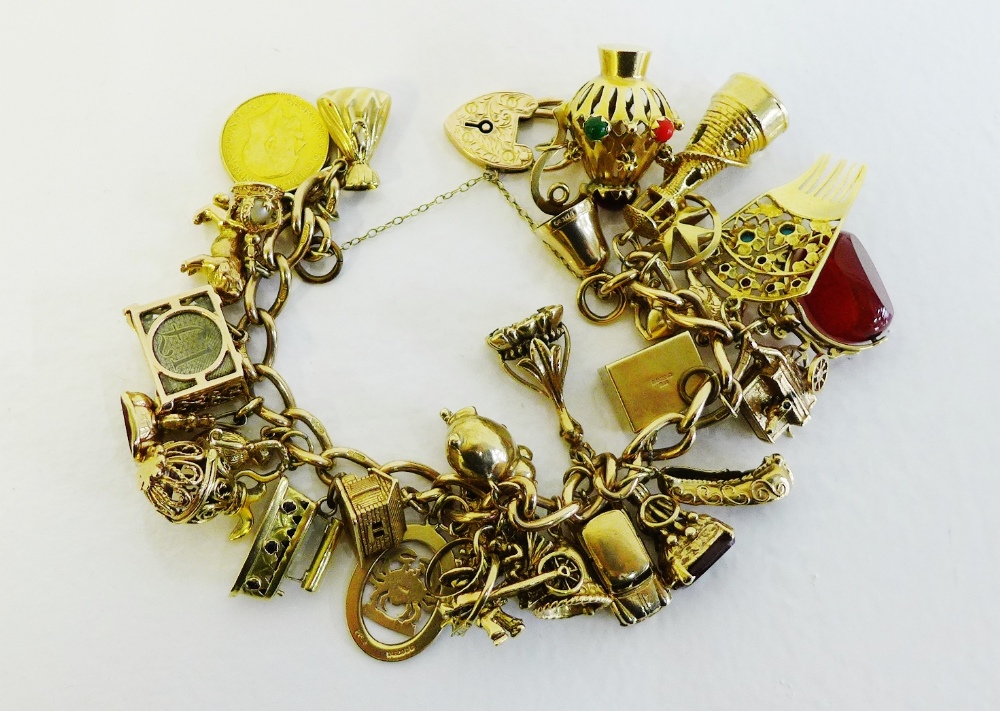 A 9 carat gold charm bracelet with heart shaped padlock hung with twenty nine mostly hallmarked