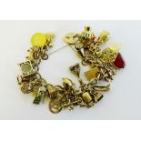 A 9 carat gold charm bracelet with heart shaped padlock hung with twenty nine mostly hallmarked