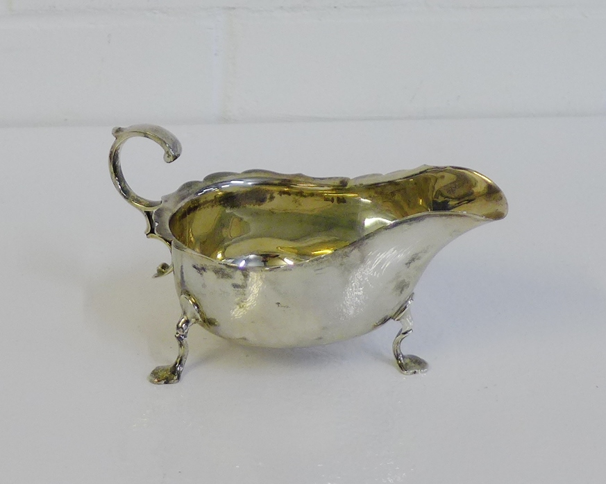 George V silver sauce boat with wavy rim and scroll handle, on pad feet, bearing makers mark for