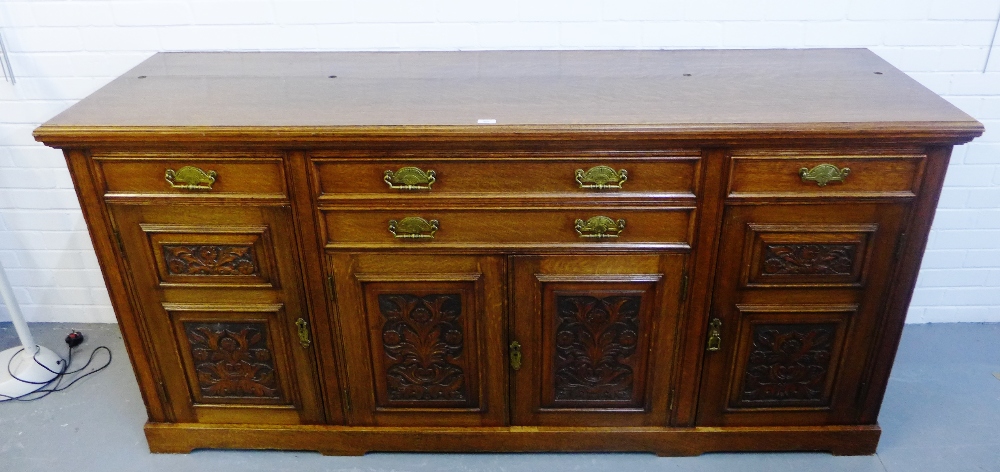 An early 20th century oak low dresser, with foliate carved cupboard doors, 98 x 206cm