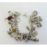A vintage silver charm bracelet hung with a selection of approx 25 silver and white metal charms