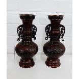 A pair of bronze twin handled vases with bird and foliage pattern in relief to the bulbous body,