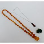 A mixed lot to include a malachite brooch, hardstone pendant on chain and a strand of amber beads (