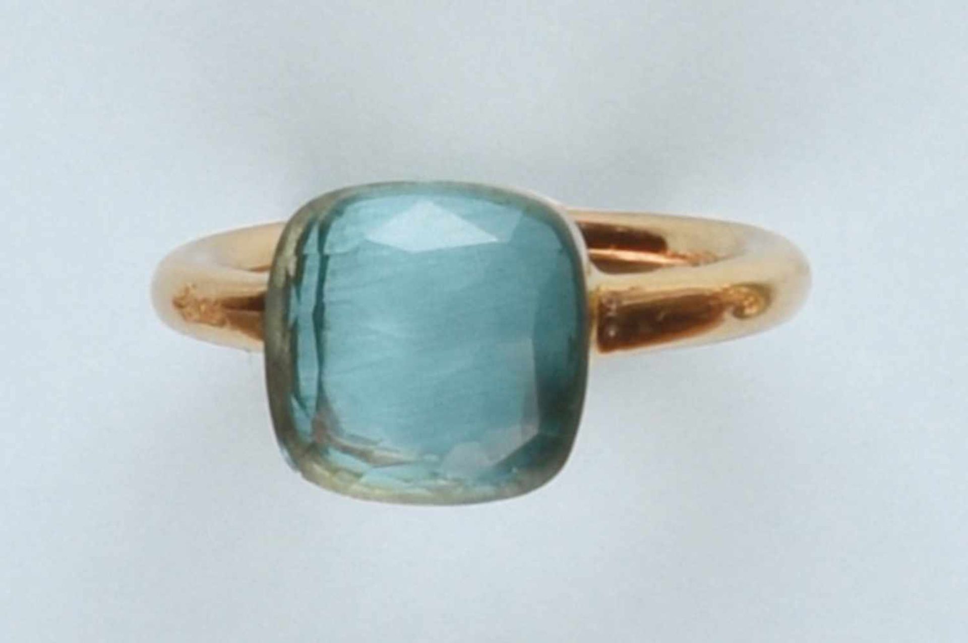 Bague en or rose 750 signée "POMELLATO", modèle "Nudo". Elle est ornée d'une topaze bleue cabochon