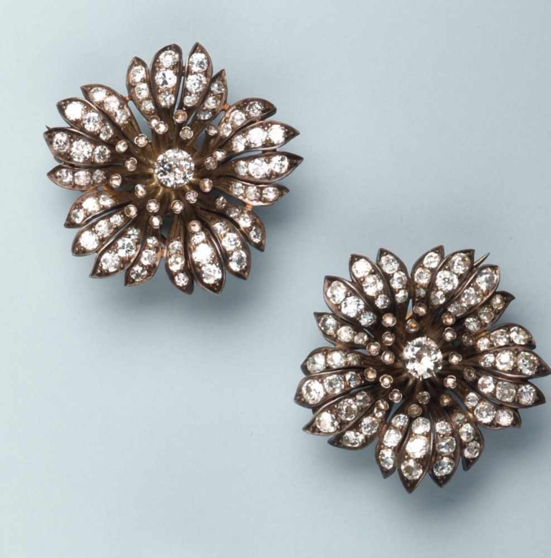 Pittoresque paire de broches en argent et or rose 750. Chaque décor stylise une fleur. Le pistil est