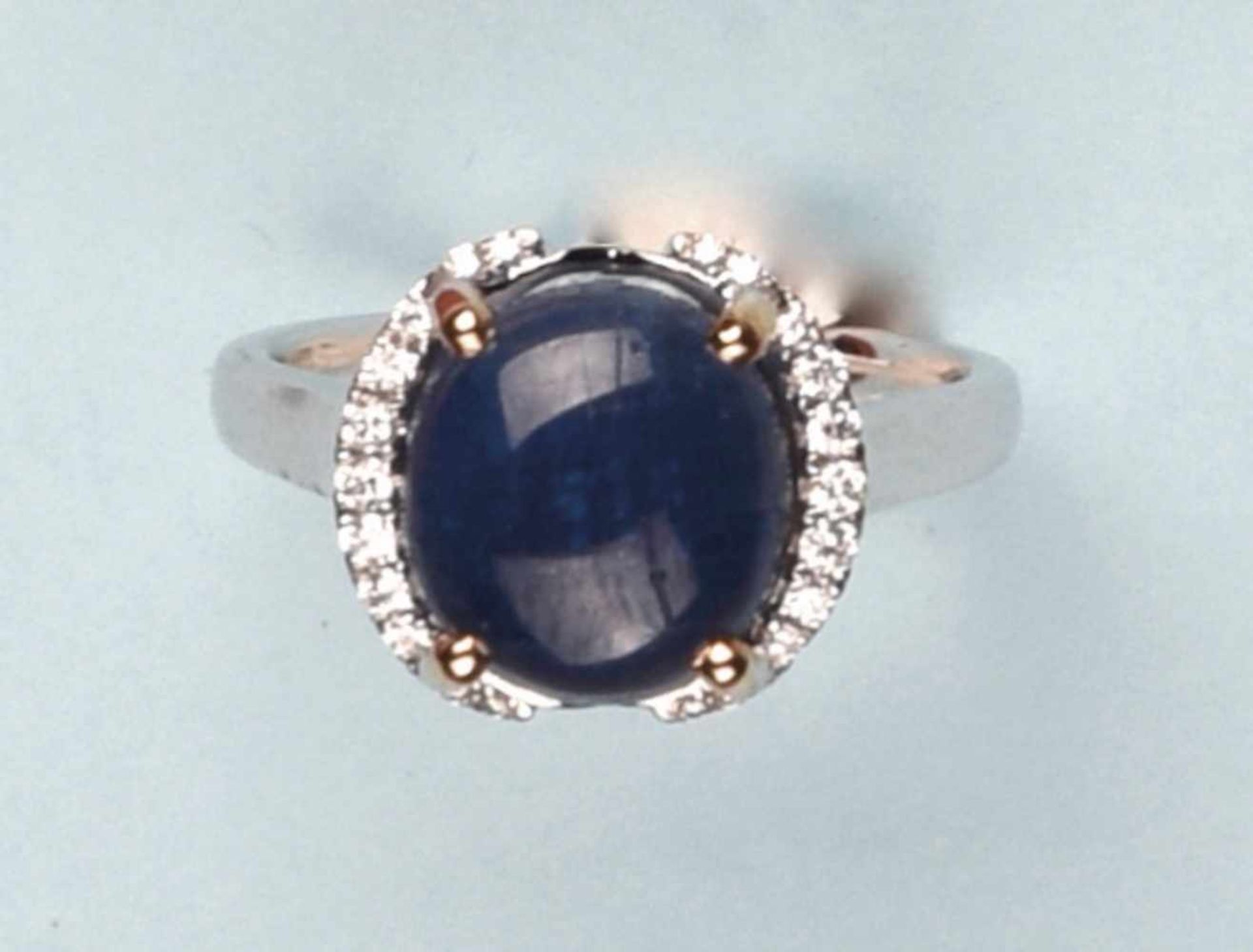 Bague en or blanc et or jaune 750. Elle est ornée d'un saphir cabochon de 5.55 cts. Il est encadré