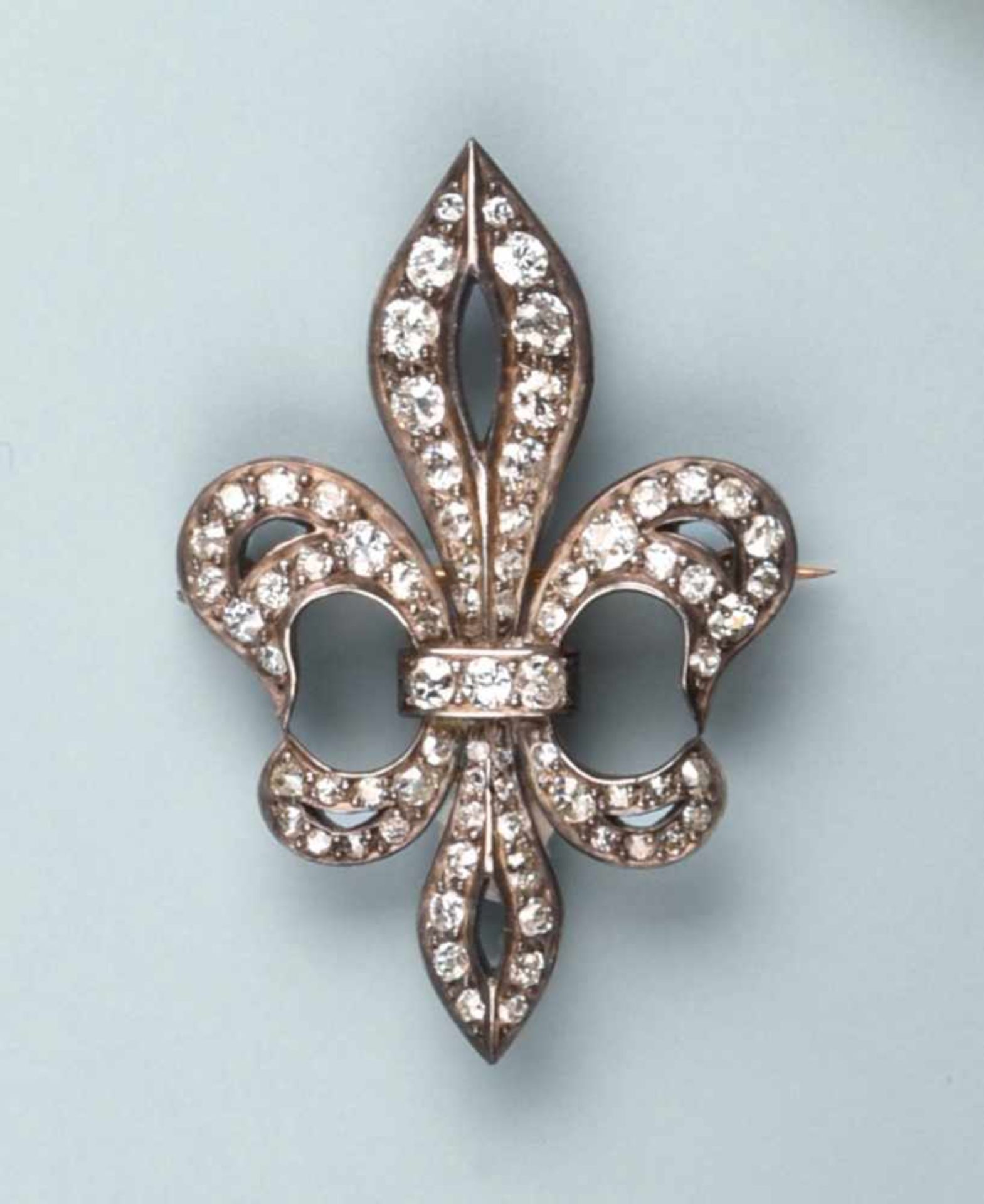 Belle broche en argent et or rose 750. Elle stylise une fleur de lys entièrement pavée de diamants