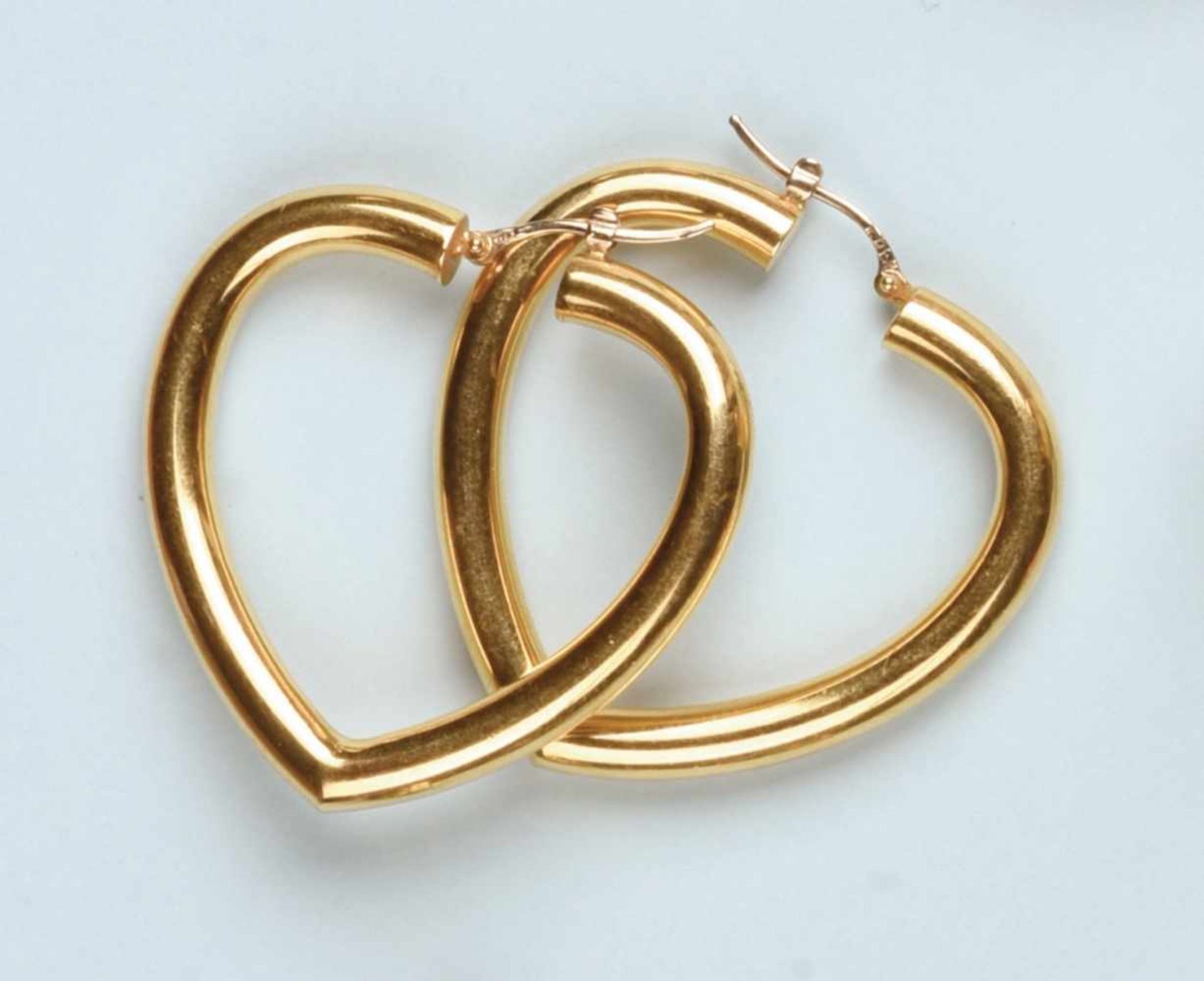 Paire de boucles d'oreilles créoles en or jaune 750 (système tige). Chaque boucle stylise un coeur à