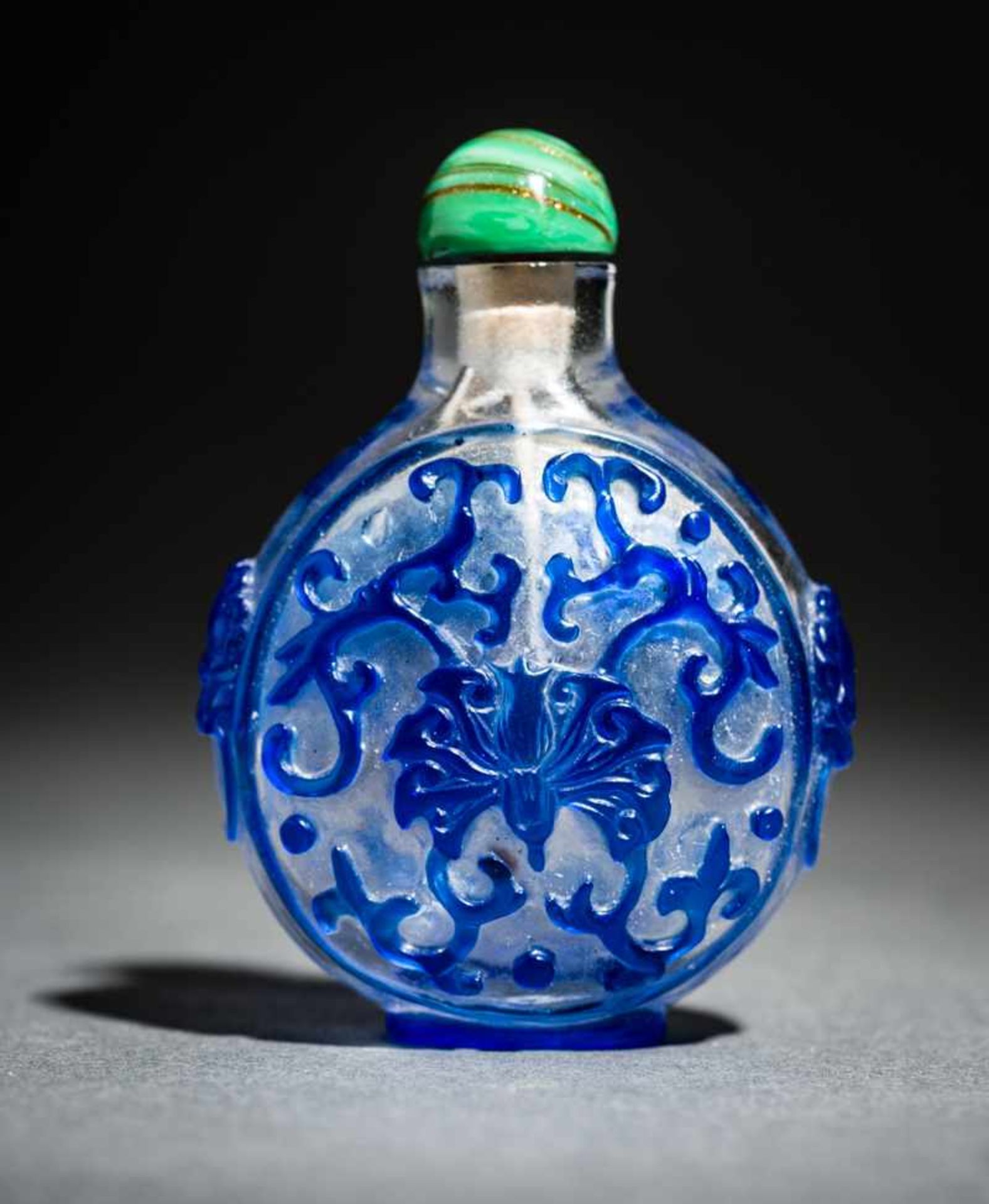 TRANSPARENTES GLASSNUFFBOTTLE MIT BLÜTEN, RANKEN, LÖWENMASKEN Überfangglas, China. Kreisrundes,