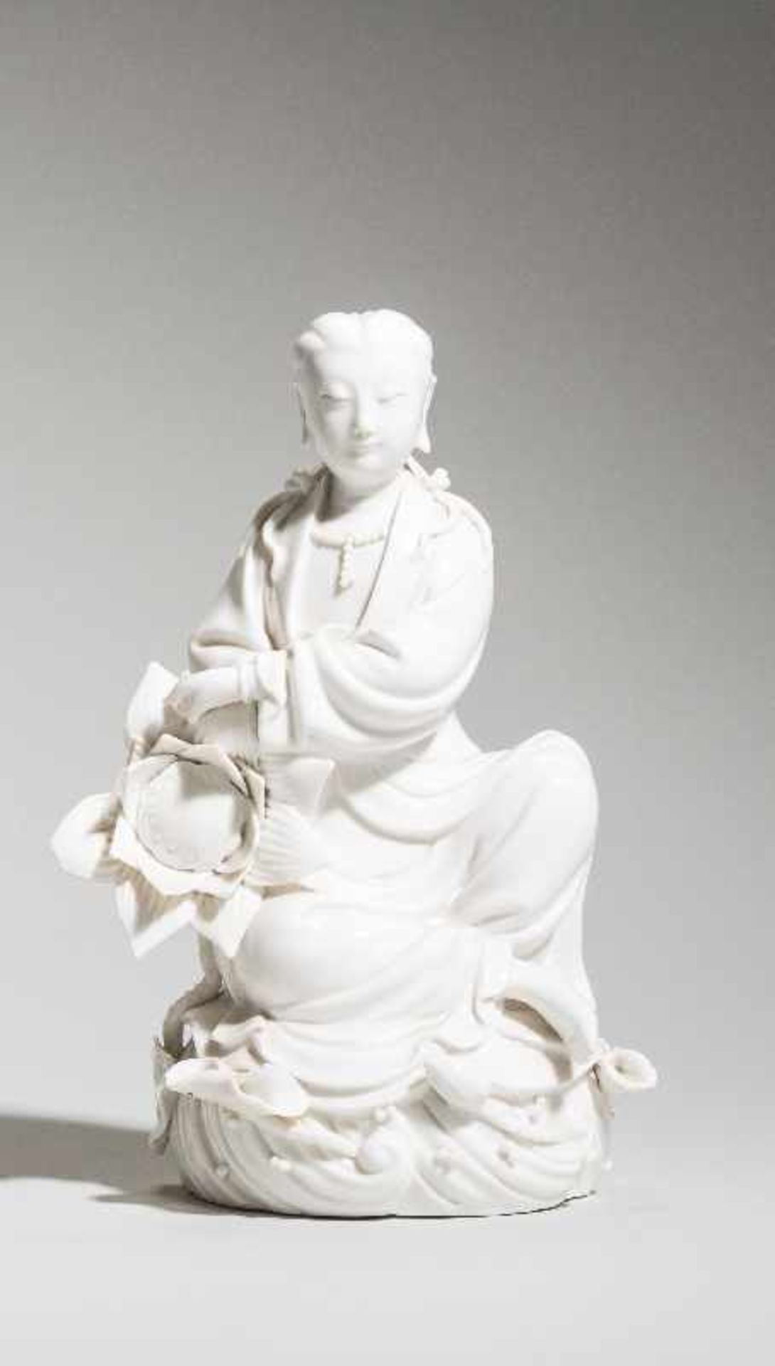 SITZENDE GUANYIN AUF WOGE Blanc de Chine. China, 20. Jh. Sitzende Göttin Guanyin auf einer Woge, mit