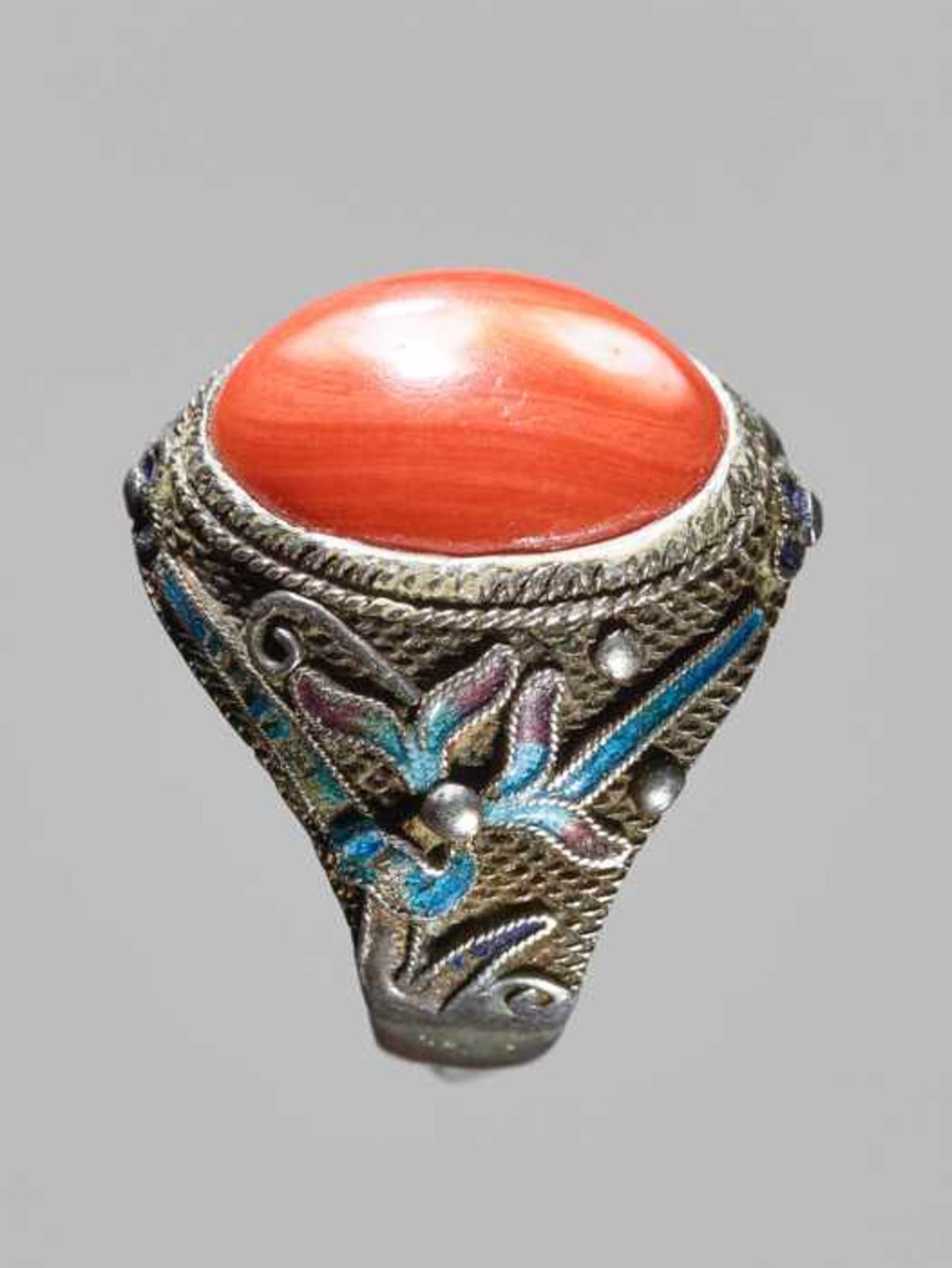 AN ENAMELED EXPORT SILVER RING WITH A LARGE CORAL CABOCHON, QING DYNASTY Silver and coral, the