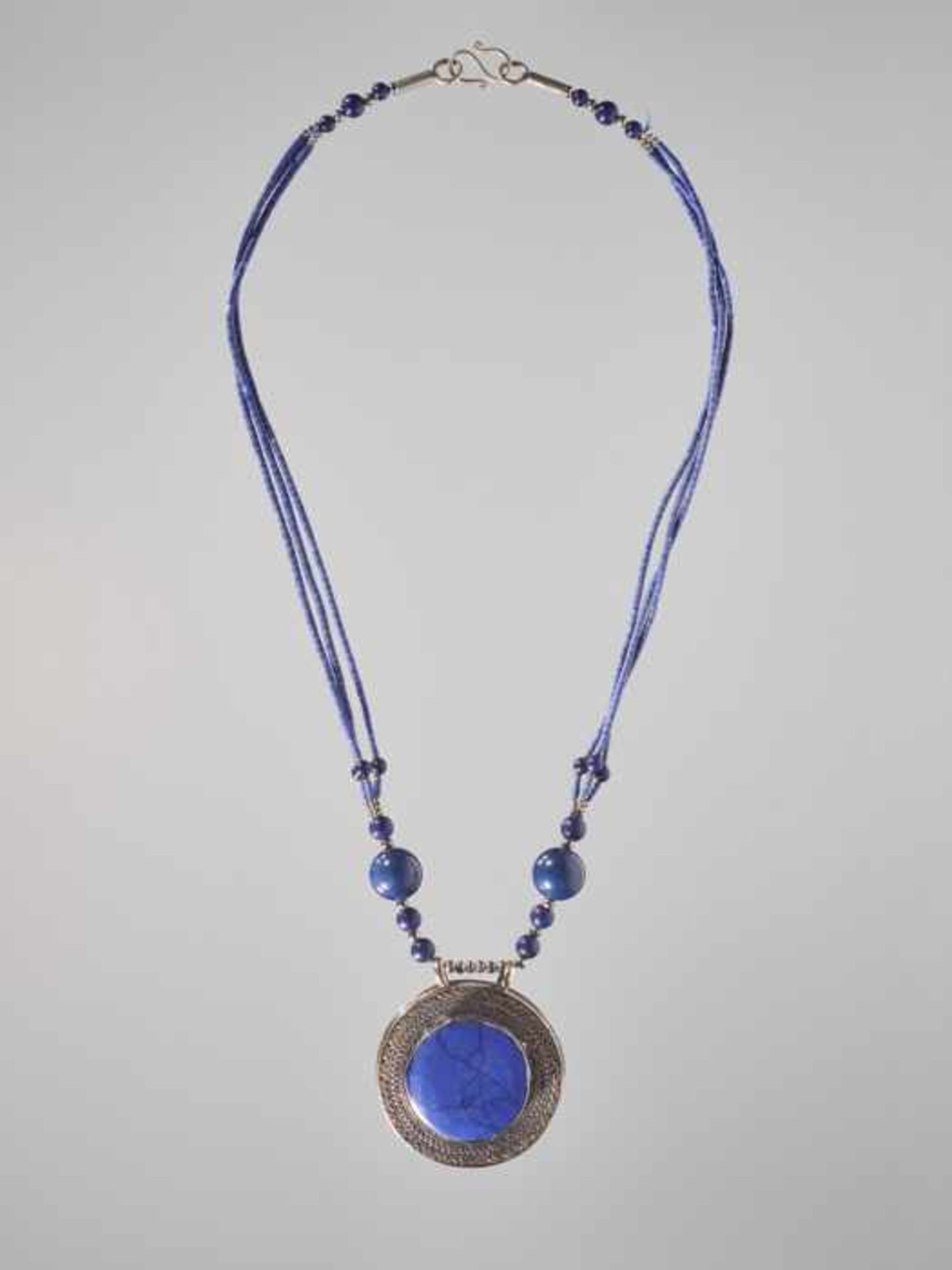 A SINO-TIBETAN SILVER AND LAPIS AMULET ON A NECKLACE, 20th CENTURY The amulet made of engraved