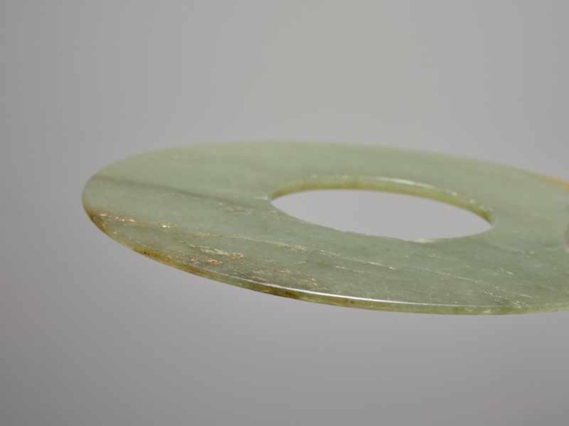 A SMOOTHLY POLISHED BI DISC WITH SHINY SURFACES CARVED FROM GREEN JADE WITH BROWN STRIPES Jade. - Image 4 of 4