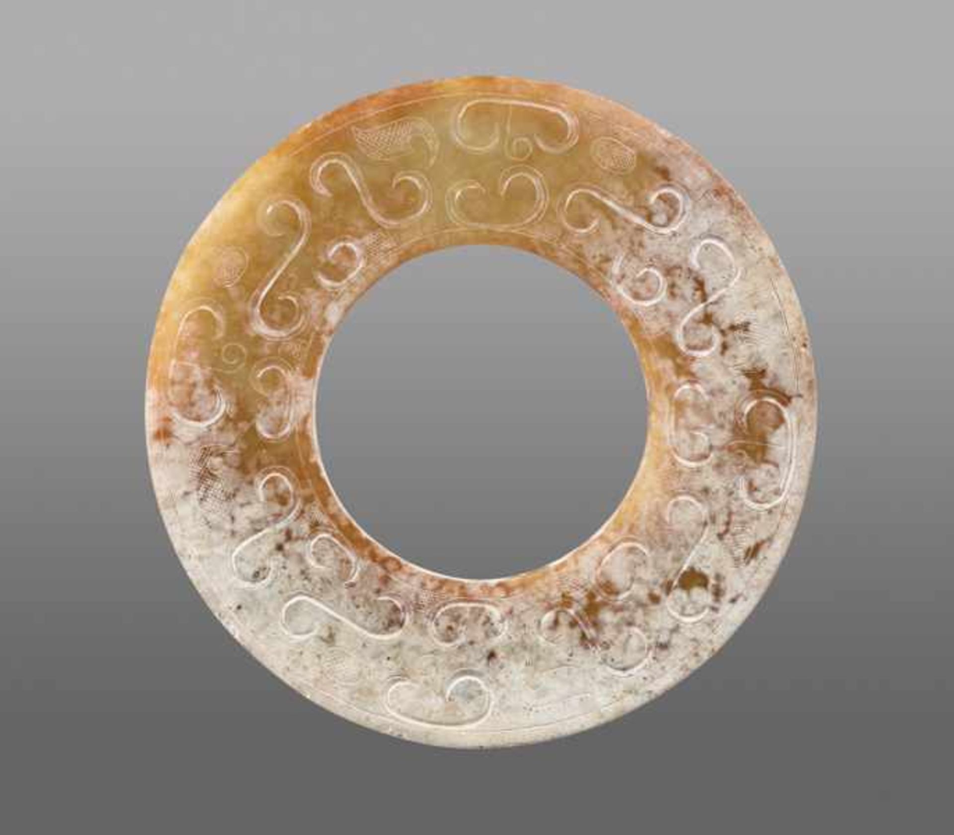 A REFINED HUAN RING WITH SUBTLY CARVED ABSTRACT-LOOKING DRAGON HEADS Jade. China, Eastern Zhou,