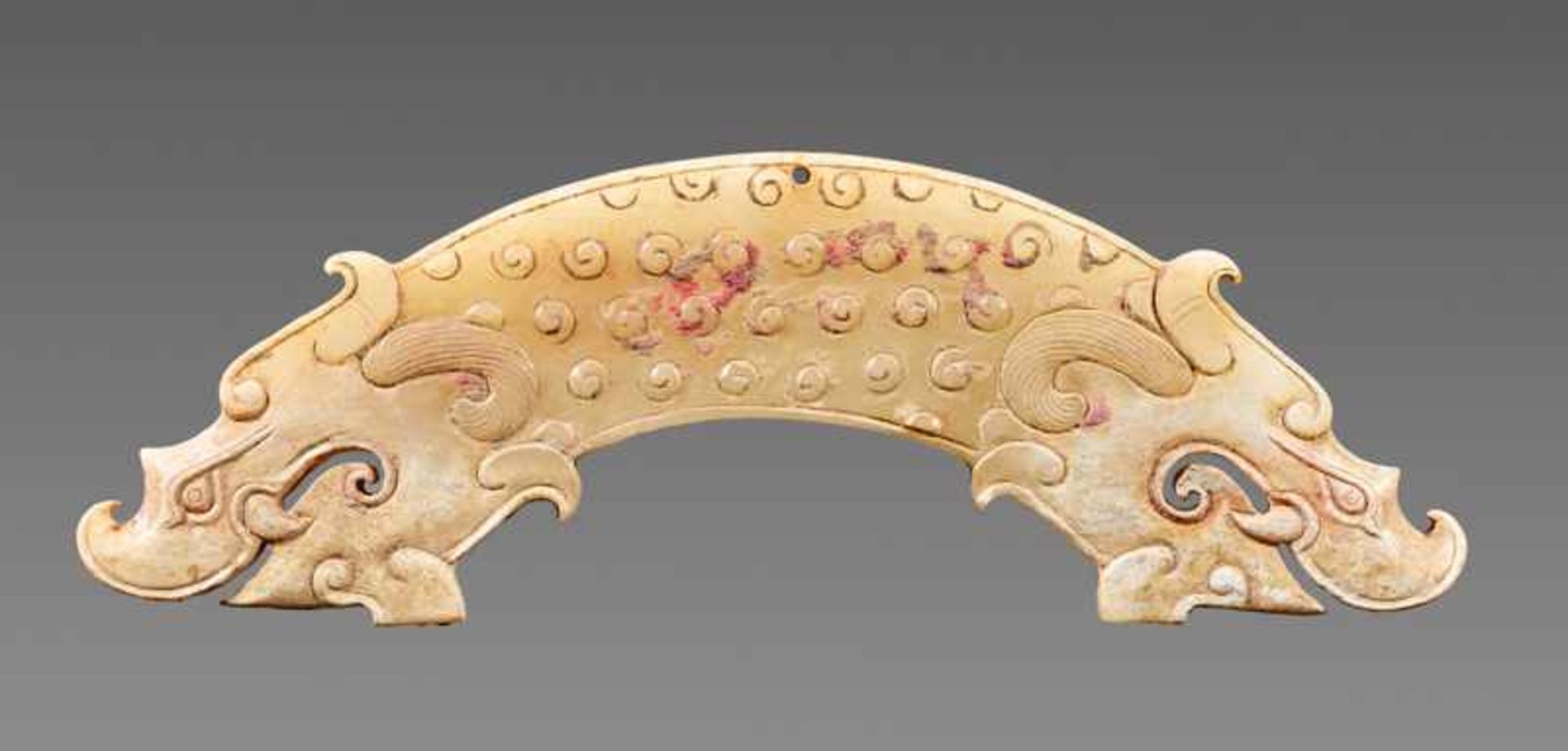 A POWERFUL HUANG ARCHED PENDANT WITH FINELY DETAILED DRAGON HEADS AND A PATTERN OF RAISED CURLS