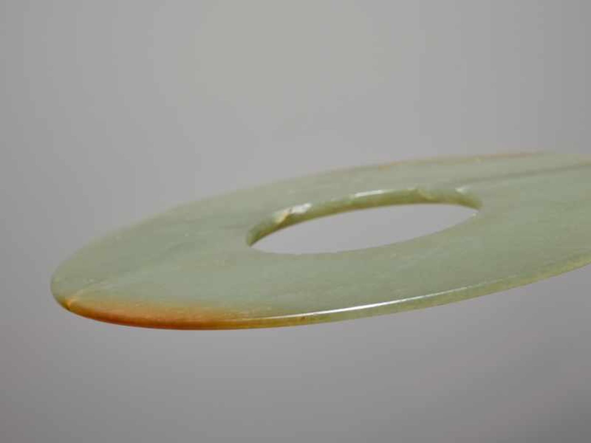 A SMOOTHLY POLISHED BI DISC WITH SHINY SURFACES CARVED FROM GREEN JADE WITH BROWN STRIPES Jade. - Image 3 of 4