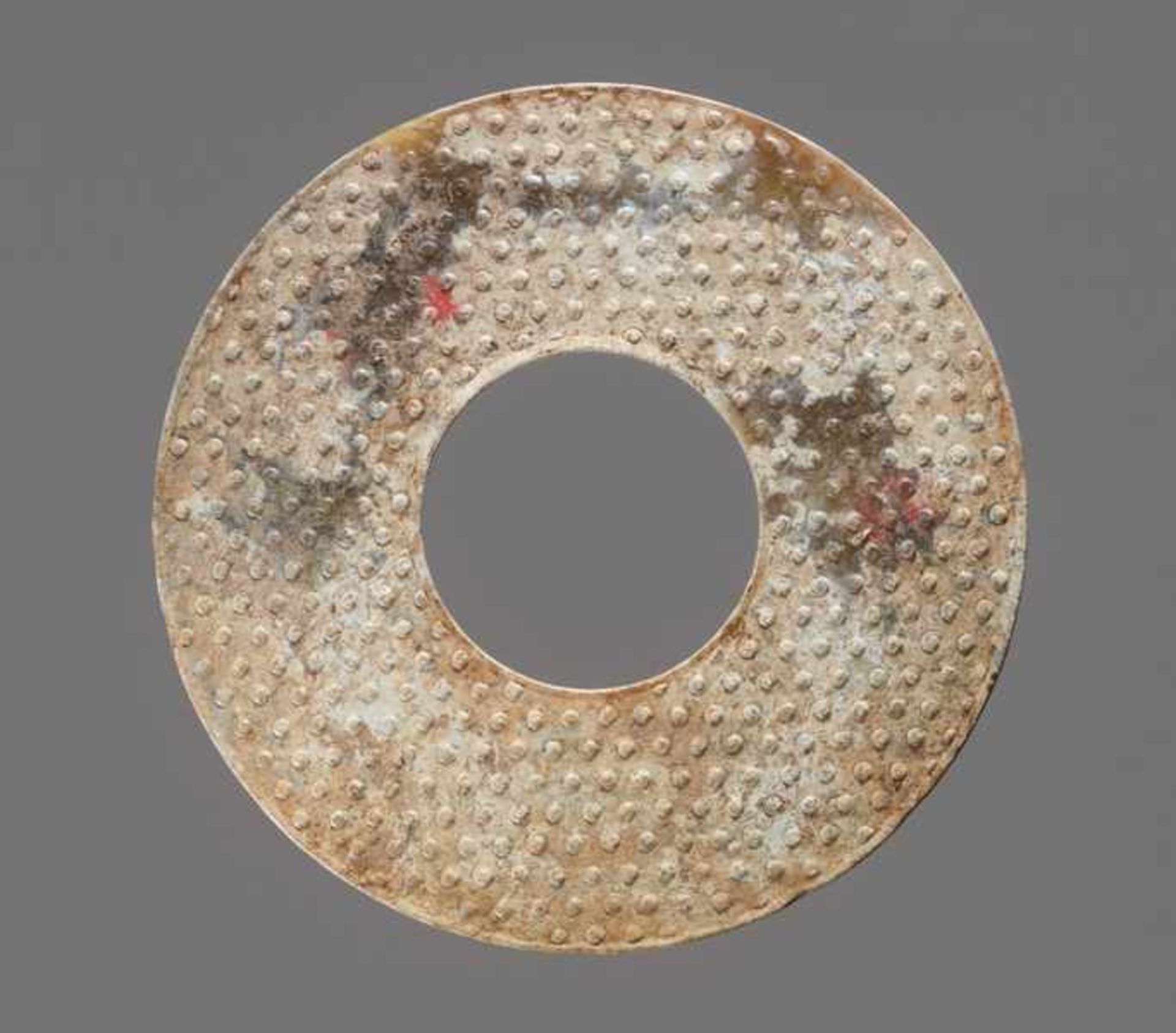 A STRONGLY CALCIFIED BI DISC WITH SCROLLS IN RELIEF Jade. China, Han dynasty, 3rd - 2nd century BC