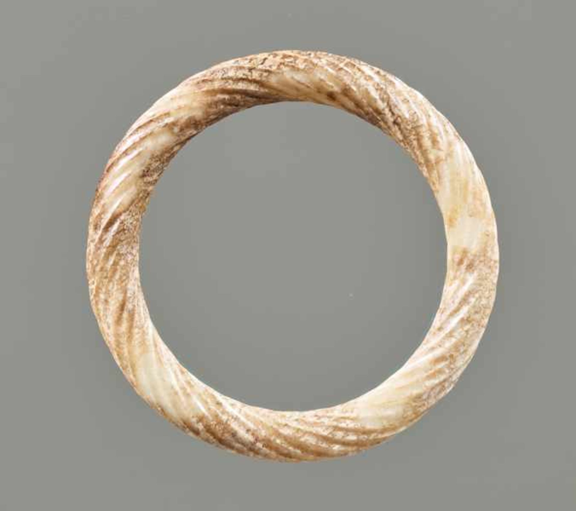 AN ORNAMENTAL RING IN PARTLY CALCIFIED WHITE JADE DECORATED WITH THE “TWISTED ROPE” PATTERN Jade.