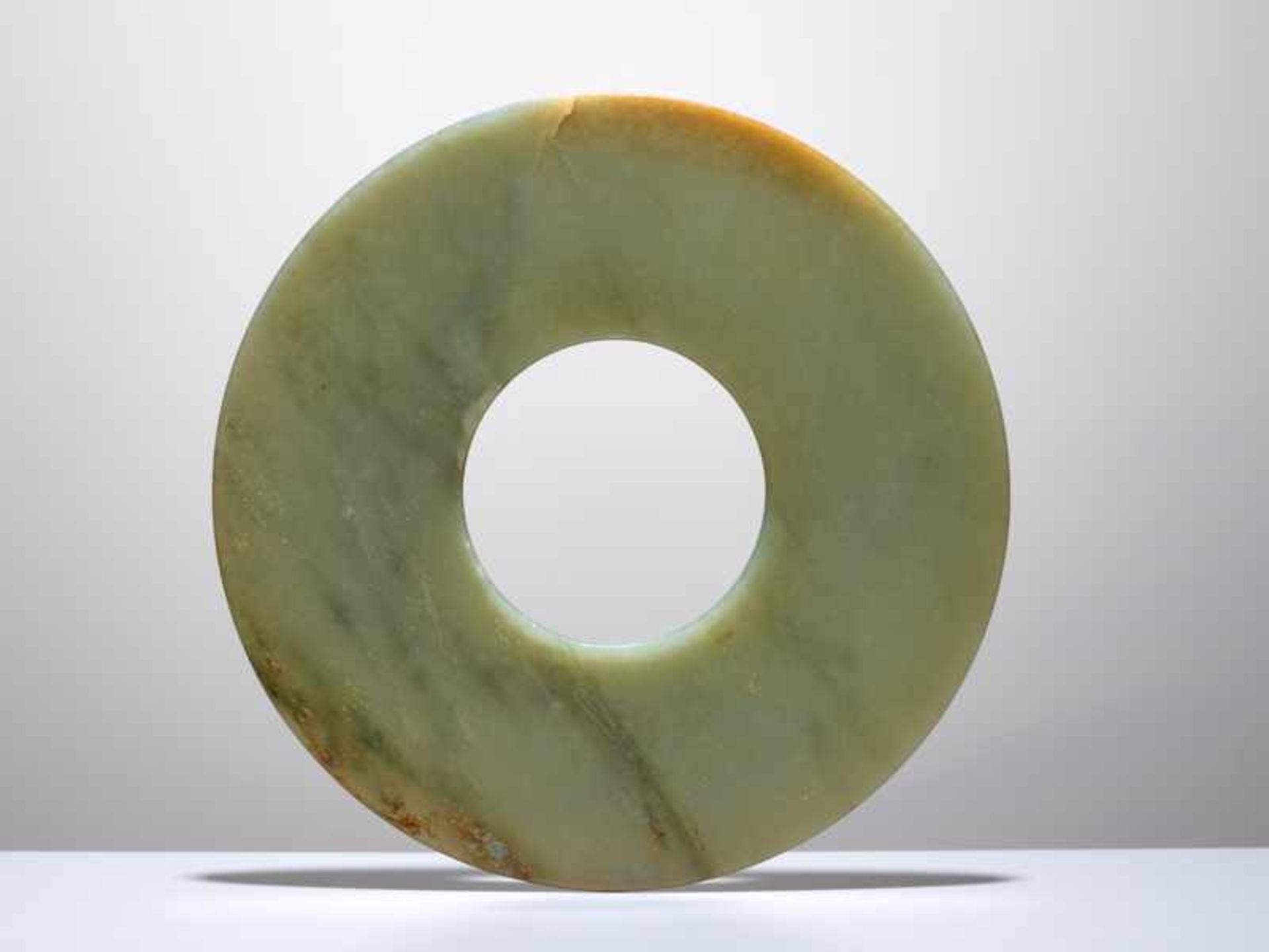 A SMOOTHLY POLISHED BI DISC WITH SHINY SURFACES CARVED FROM GREEN JADE WITH BROWN STRIPES Jade. - Image 2 of 4