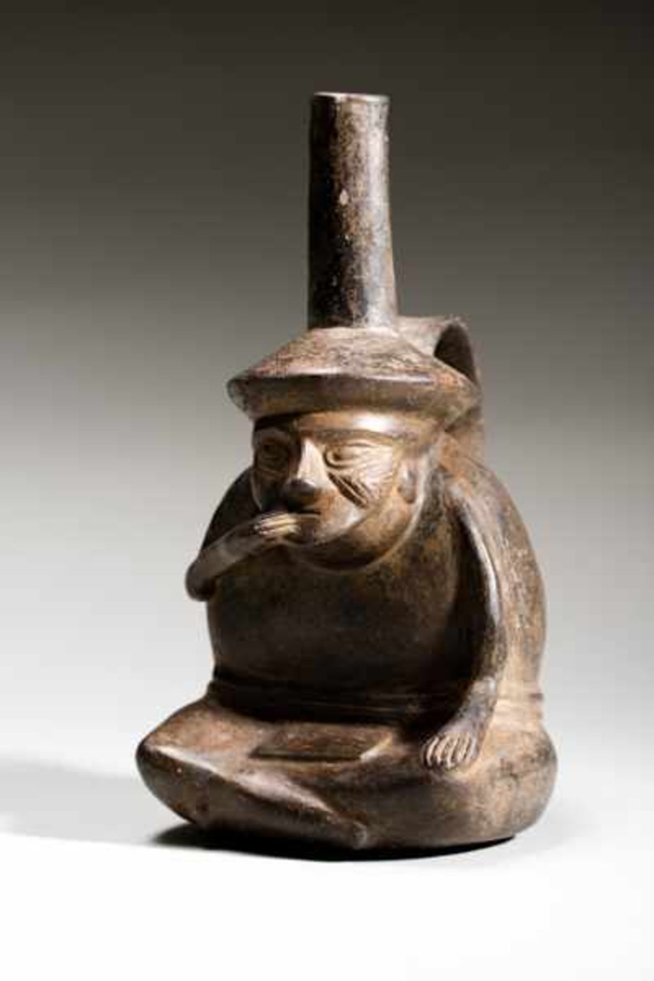 VESSEL WITH HANDLE IN THE SHAPE OF A SITTING MAN Terracotta. Lambayeque, Peru, ca. 1200Black-gray