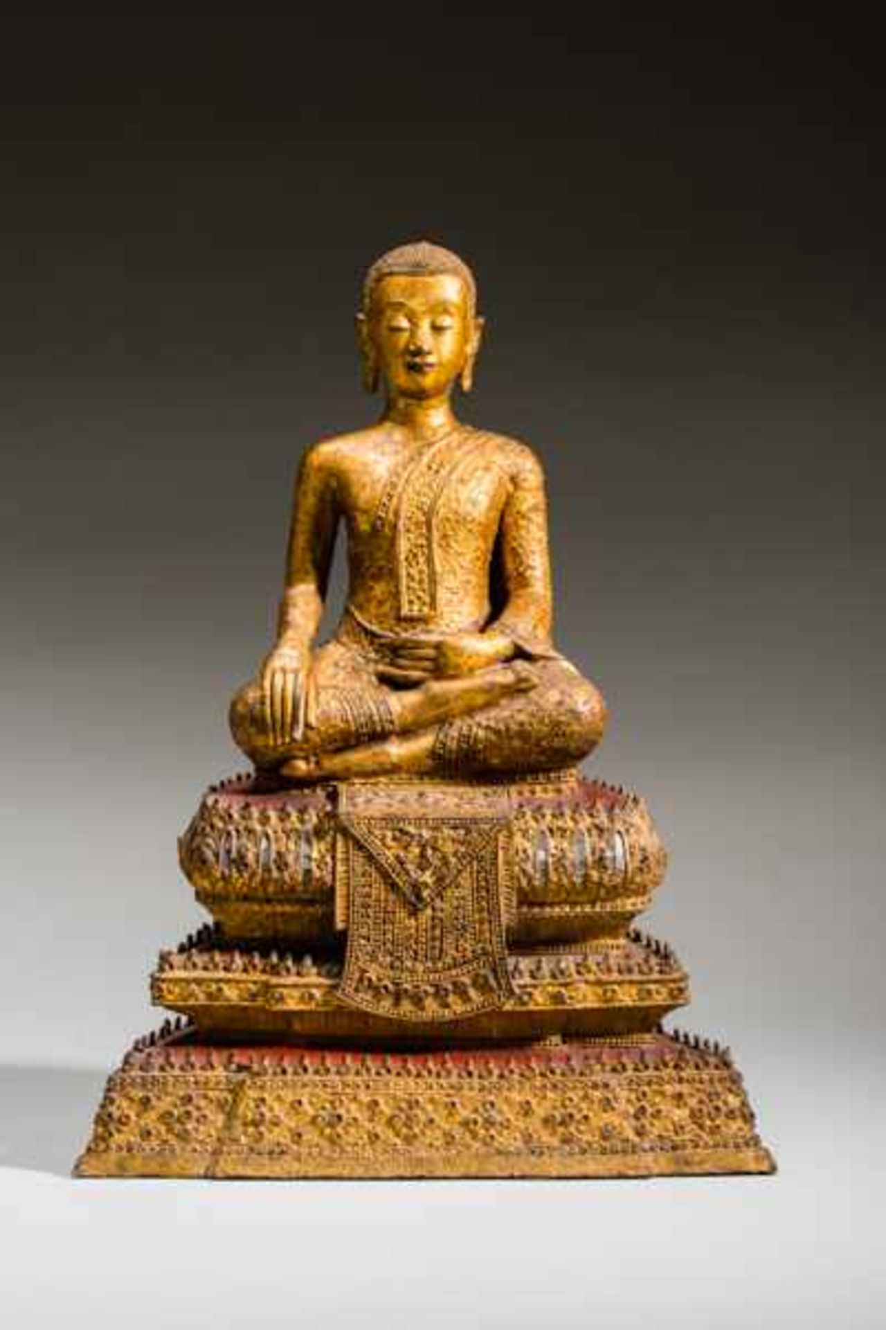 ARHAT SEATED IN THE STYLE OF BUDDHA Gilded bronze. Siam, Ratanakosin, about 1800Opulently wrought