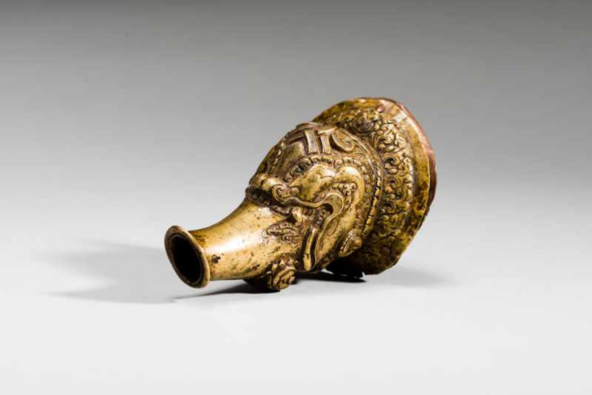 HEAD OF A MYTHICAL CREATURE Yellow bronze. Tibet, ca. 18th to 19th cent.This interesting piece is
